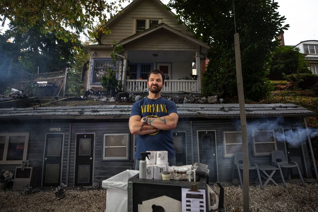 Richard Knowles, with a maid cart, in front of his mini Bates Motel on Queen Anne. (Bettina Hansen / The Seattle Times)