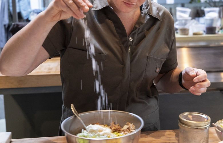 Wed. July 7, 2021.    Pacific Taste.       Chef Liz Kenyon from Manolin in Fremont prepares her version of their ultimate tuna salad sandwhich.    Adding salt before stirring everything together.  217519