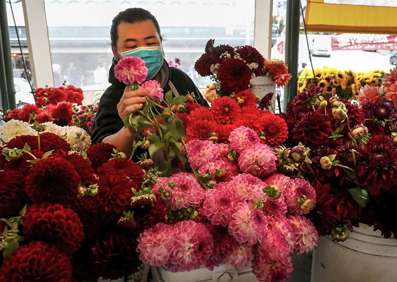 Scott Chang with See Lee Gardens builds bouquets at his family’s Pike Place Market stall. The business is also now selling flowers at other outlets. (Alan Berner / Alan Berner)