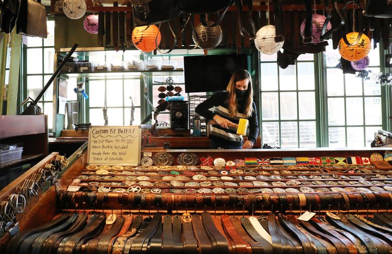 Devynn Patterson, at Marakesh Leather, sells custom belts in Pike Place Market. The stand has been there since 1971. (Alan Berner / The Seattle Times)