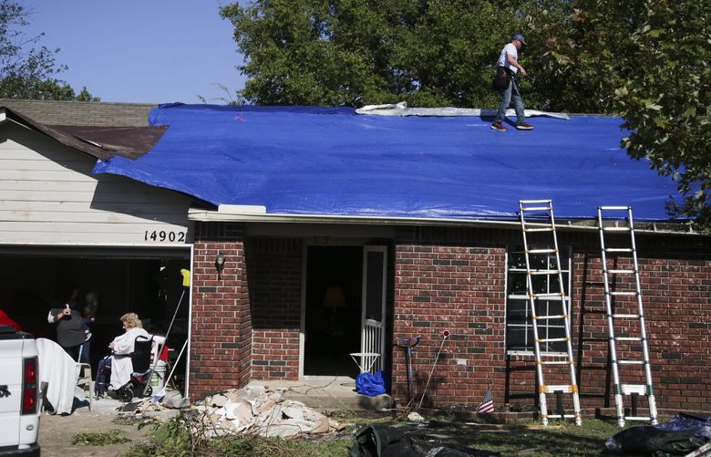 C&C roofing and home repair’s Jeremy Conn begins repairs on a home’s damaged roof on Monday, Oct. 11, 2021 in Coweta, Okla. The Conn and his team work fast to cover up the large hole left in the roof. (Michael Noble Jr./Tulsa World via AP)