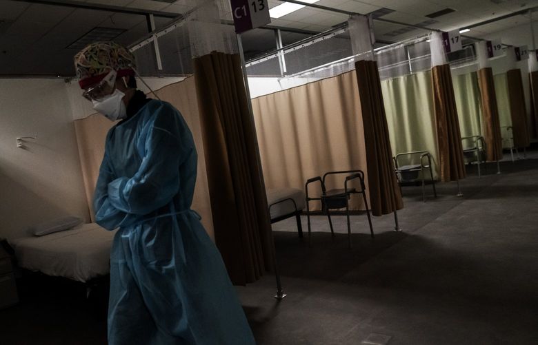 Registered traveling nurse Patricia Carrete, of El Paso, Texas, walks down the hallways during a night shift at a field hospital set up to handle a surge of COVID-19 patients, Wednesday, Feb. 10, 2021, in Cranston, R.I. Rhode Island’s infection rate has come down since it was the highest in the world two months ago and many of the field hospital’s 335 beds are now empty. On quiet days, the medical staff wishes they could do more. (AP Photo/David Goldman)