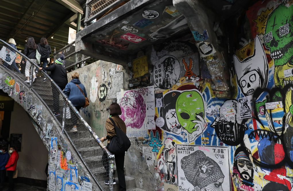 The wall in Upper Post Alley is always covered in posters and miscellaneous art. The steps lead up to Rachel the Pig. (Alan Berner / The Seattle Times)