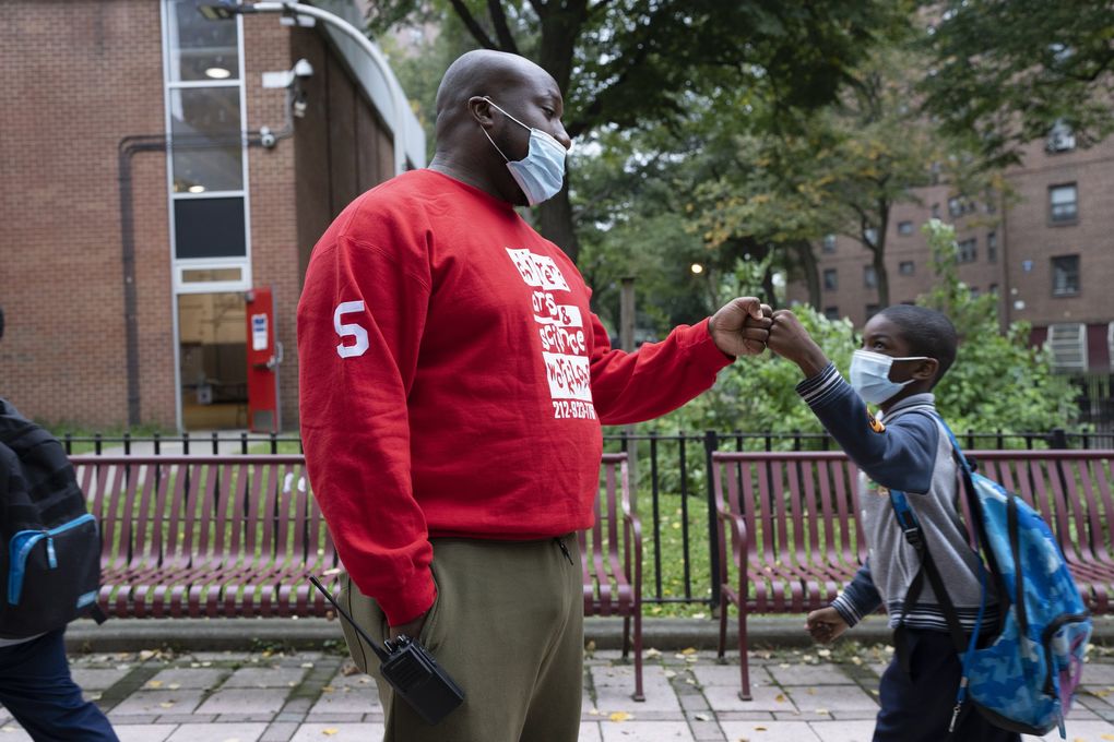Jarrell Hughes, an educator, greets children as they arrive for after-school programs in New York. (James Estrin / The New York Times)