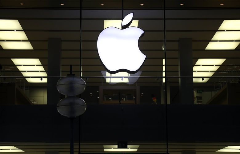 FILE – This Dec. 16, 2020 file photo shows an illuminated Apple logo at a store in Munich, Germany. Apple has released a critical software patch to fix a security vulnerability that researchers say could allow hackers to directly infect iPhones and other Apple devices without any user action. (AP Photo/Matthias Schrader, File)