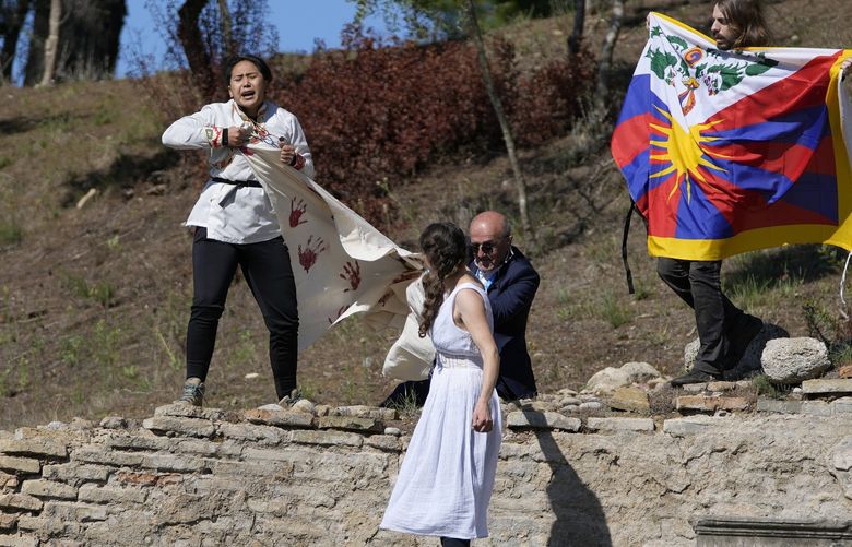 Police officers run to detain protesters displaying a Tibetan flag and a banner disrupting the lighting of the Olympic flame at Ancient Olympia site, birthplace of the ancient Olympics in southwestern Greece, Monday, Oct. 18, 2021. The flame will be transported by torch relay to Beijing, China, which will host the Feb. 4-20, 2022 Winter Olympics. (AP Photo/Thanassis Stavrakis) XAF112 XAF112