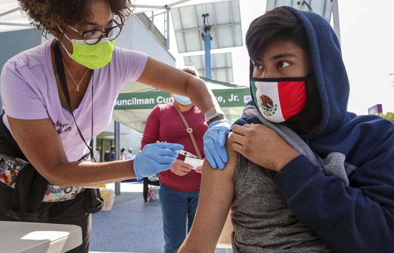 Los Angeles, CA – June 24: Nurse Marie Eddins, left, administers COVID19 vaccine to 14-year-old Emanuel Coyote at mobile clinic held at Los Angeles City Councilman Curren Price’s district office. After getting vaccine Coyote got a free pair of Beats by Dre” headphones at Councilman Curren Price’s district office on Thursday, June 24, 2021 in Los Angeles, CA. (Irfan Khan / Los Angeles Times)