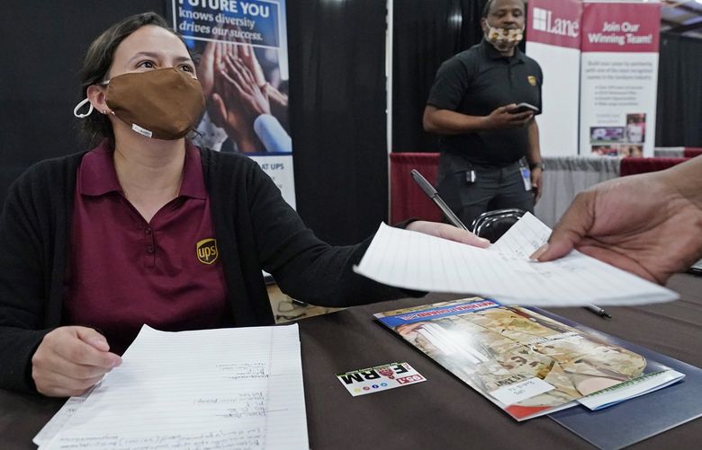 Ariel Jones, a United Parcel Service human resources intern, hands an applicant an information sheet, while the human resources specialist for the company, Mareno Moore, right, monitors the interaction during the Lee County Area Job Fair in Tupelo, Miss., Tuesday, Oct. 12, 2021. Employers representing a variety of manufacturing, production, service industry, medical and clerical companies attended the day long affair with an eye towards recruitment, hiring, training and retention. (AP Photo/Rogelio V. Solis)