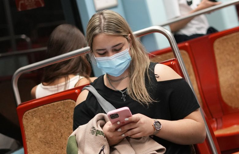 A woman wearing a face mask uses her cellphone in a subway train in Lisbon, Friday, Oct. 22, 2021. Portugal has scrapped many of its remaining COVID-19 restrictions but the wearing of face masks is still mandatory on public transport, in hospitals and care homes, and in shopping malls. (AP Photo/Armando Franca) XAF101 XAF101