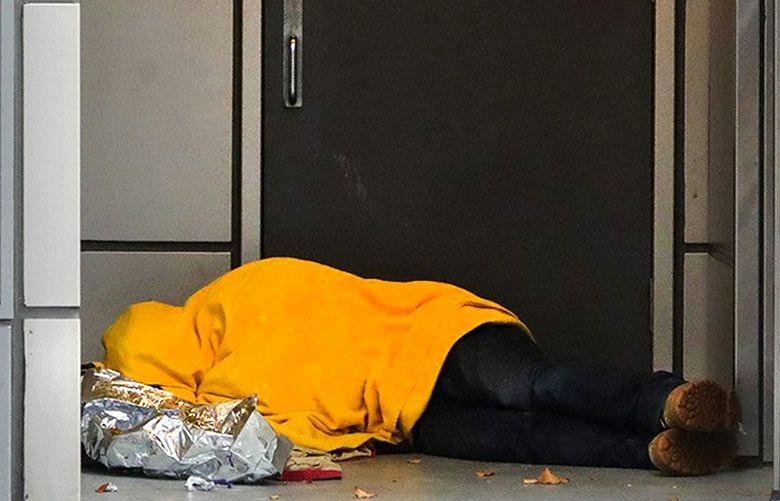 A homeless person sleeps in an alcove on the sidewalk on Pine Street, near Westlake Park in Downtown Seattle. 218598
