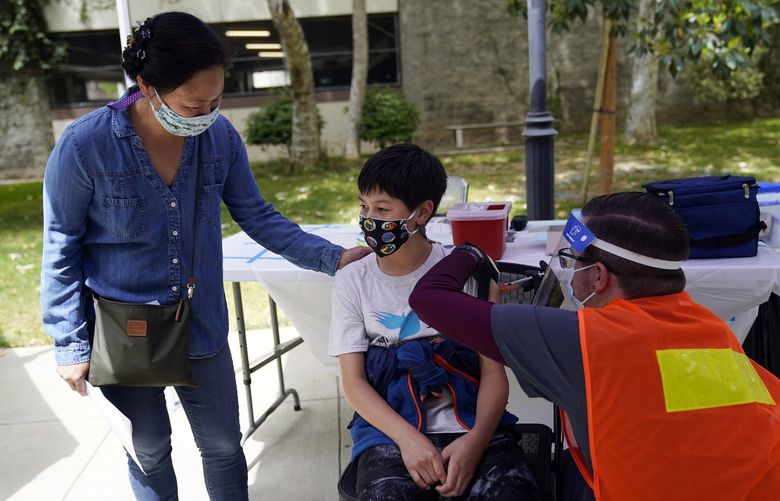 FILE – In this May 14, 2021, file photo, Colin Sweeney, 12, gets a shot of the Pfizer COVID-19 vaccine as his mother Nicole pats his shoulder at the First Baptist Church of Pasadena in Pasadena, Calif. Public health departments across California are gearing up to administer coronavirus vaccines to children ages 5 to 11 in the coming weeks and officials say they are planning “family-friendly” events, including at schools, to convince parents to get their kids the shots. The White House on Wednesday, Oct. 20, detailed plans for the expected authorization of the Pfizer shot for elementary school youngsters in a matter of weeks. (AP Photo/Marcio Jose Sanchez, File) LA451 LA451