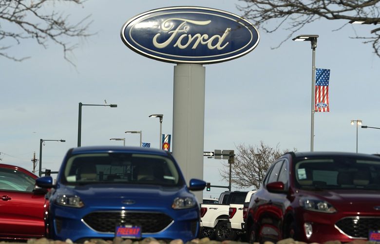 In this Sunday, April 25, 2021, photograph, the blue oval logo of Ford Motor Company is shown over a row of unsold 2021 Escapes at a dealership in east Denver. The global computer chip shortage cut into third-quarter profits at both Ford and crosstown rival General Motors, with both companies having to temporarily close factories, pinching supplies on dealer lots, according to results announced Wednesday, Oct. 27. (AP Photo/David Zalubowski) NYSB303 NYSB303