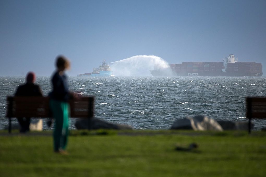 The Maersk Trader, left, sprays down the Zim Kingston, right, a container ship that caught fire off the coast of Vancouver Island near Victoria, B.C. on Sunday. (James MacDonald / Bloomberg)