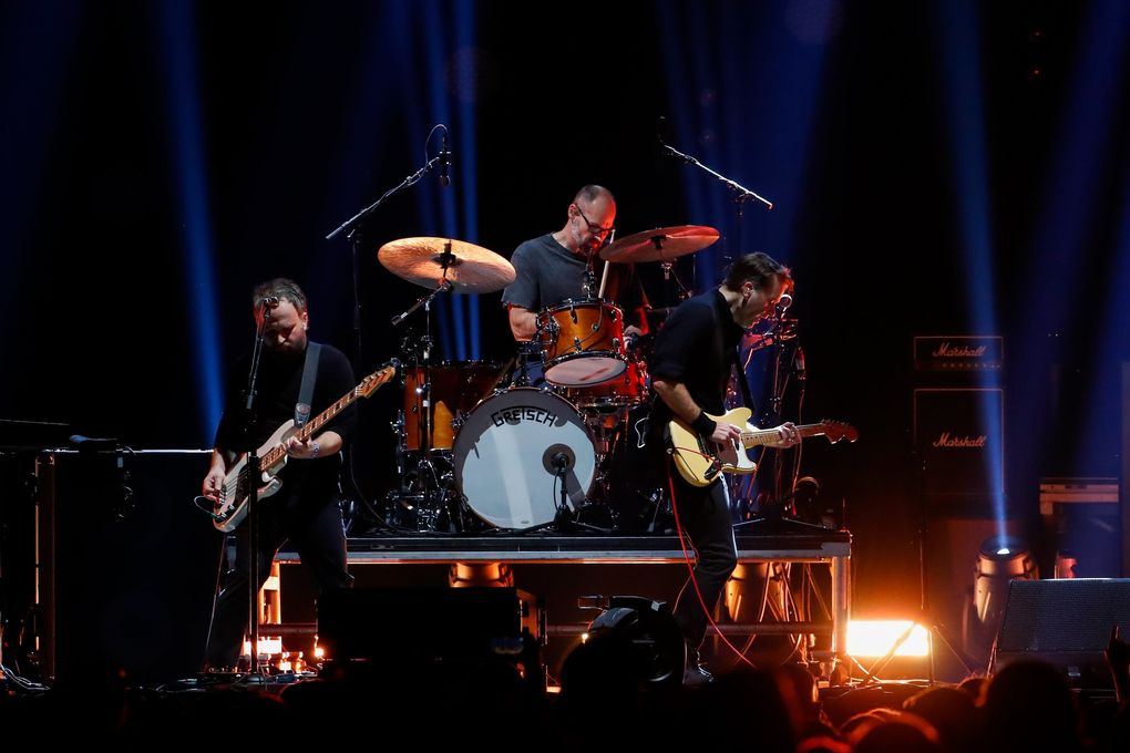 Nick Harmer, left, drummer Jason McGerr and lead singer Ben Gibbard of Death Cab for Cutie perform Tuesday at Climate Pledge Arena in Seattle. (Jennifer Buchanan / The Seattle Times)