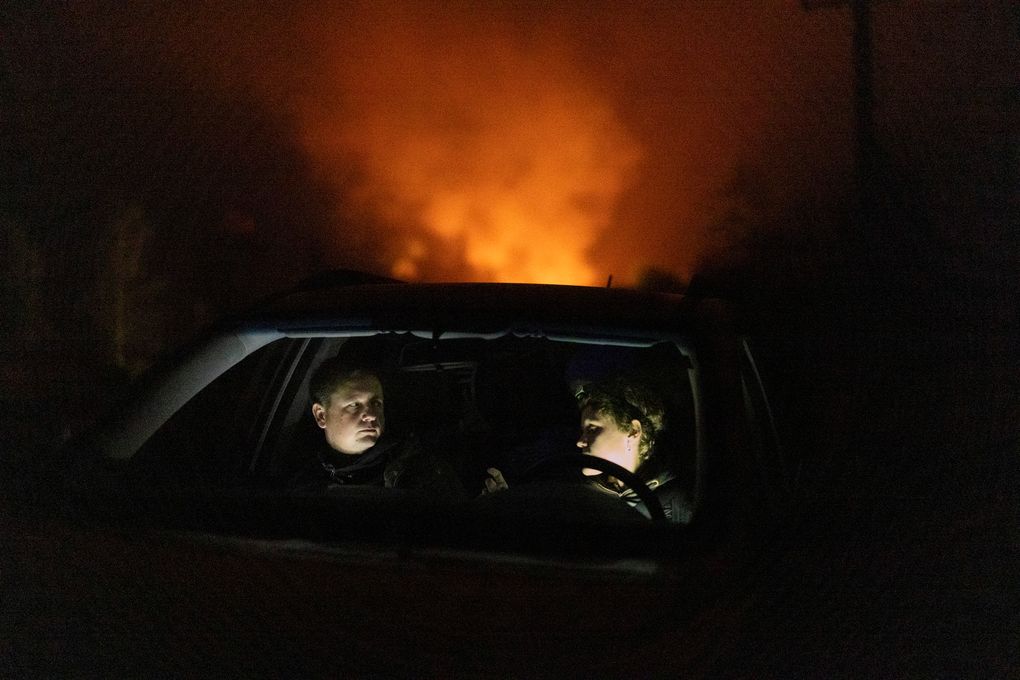 Piotr Bystrianin and Dorota Nowok of a refugee aid group wait in a car for a signal from a family of migrants they have been helping in Poland near the border with Belarus early on Oct. 2, 2021. One father had to decide whether to save an ailing baby girl and risk being expelled. (Maciek Nabrdalik / The New York Times)