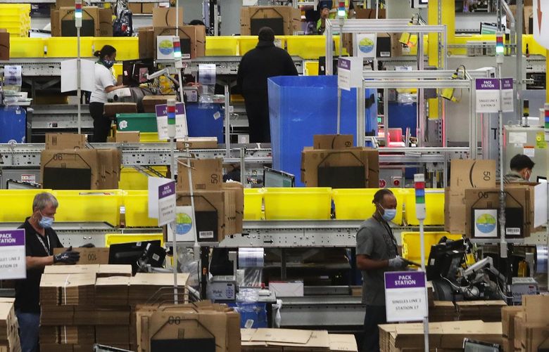 Employees at packing stations are seen at Amazon’s Kent fulfillment center, a showpiece for the company’s coronavirus response, Thursday, June 11, 2020.
 214215