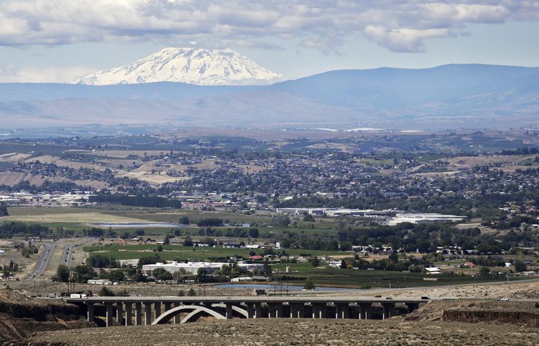 Mount Adams rises in the distance beyond the the Yakima Valley, in Yakima, Wash., June 17, 2020. The coronavirus pandemic is hitting Yakima County hard, with cases surging far faster in than in the rest of the state. The virus has caused turmoil in the farm and food processing industries, where some fearful workers staged wildcat strikes recently to demand that employers provide safer working conditions. (AP Photo/Elaine Thompson) WAET204