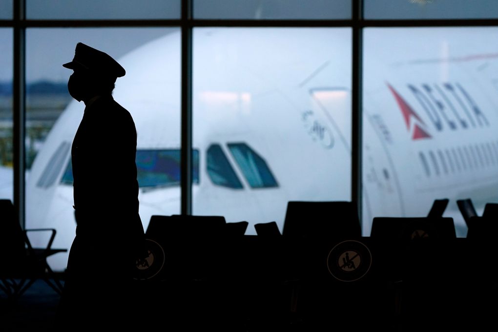 A Delta Airlines pilot wears a face mask as he walks through a terminal last winter at Hartsfield-Jackson International Airport in Atlanta. On Friday, Oct. 15, The Associated Press reported on stories circulating online incorrectly claiming a Delta Airlines pilot who had recently been vaccinated for COVID-19 died mid-flight within the last 10 days, forcing the plane to make an emergency landing. (AP Photo/Charlie Riedel, File)