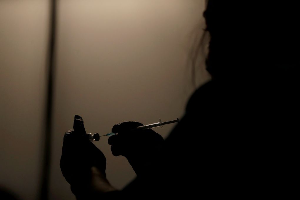 On Friday, Oct. 15, The Associated Press reported on stories circulating online incorrectly claiming a video shows people dropping “dead” outside a COVID-19 vaccination clinic in London after receiving a shot. Above, a volunteer vaccinator prepares to administer a dose of the coronavirus vaccine at a vaccine center in Neasden, north London, on May 1. (AP Photo/Matt Dunham, File)