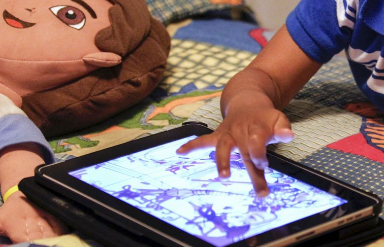 FILE – In this Friday, Oct. 21, 2011, file photo, a child plays with an iPad in his bedroom. Parents of small children have long been hearing about the perils of â€œscreen time.â€ And with more screens, itâ€™s only getting worse. But working, taking care of children and remembering to eat is exhausting. Parents need those minutes of quiet. So maybe itâ€™s time to relax a little. (AP Photo/Gerald Herbert, File) NYBZ442