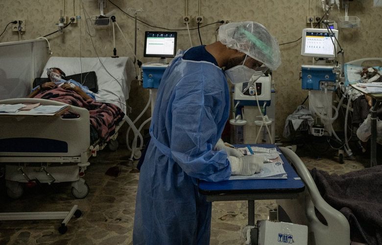 A medical worker checks on a covid-19 patient in the intensive care unit at al-Ziraa Hospital in Idlib, Syria, on Oct. 12, 2021. (Photo for The Washington Post by Nicole Tung)