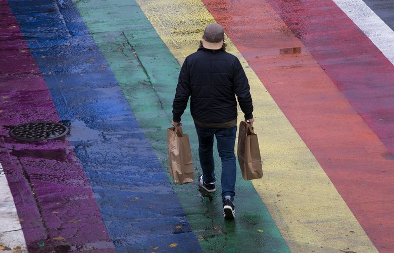 A shopper crosses the street at the intersection of E. Pike St. and Broadway in Seattle’s Capitol Hill neighborhood Thursday, October 28, 2021. Rain is expected Friday, but the weekend is predicted to be sunny. 218667