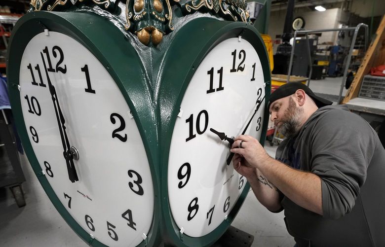 Clock technician Dan LaMoore, of Woonsocket, R.I., adjusts clock hands on a large outdoor clock under construction at Electric Time Company, Tuesday, Nov. 2, 2021, in Medfield, Mass. Daylight Saving Time ends Sunday, Nov. 7, 2021, at 2:00 a.m., when clocks are set back one hour. (AP Photo/Steven Senne) MASR109 MASR109