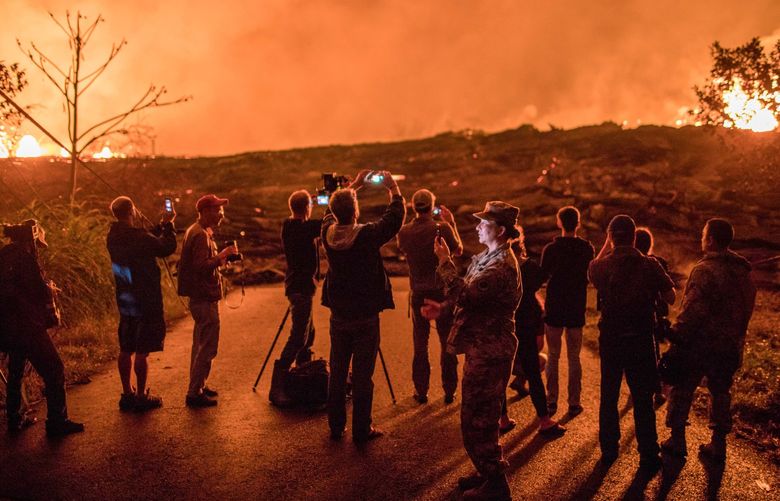 **EMBARGO: No electronic distribution, Web posting or street sales before TUESDAY 3:01 A.M. ET NOV. 9, 2021. No exceptions for any reasons. EMBARGO set by source.**  FILE — Members of the media and other bystanders watch lava flowing from Kilauea in the Leilani Estates area of Hawaii, May 24, 2018. Scientists learned lessons from the 2018 outburst on the island of Hawaii that are changing how responders prepare for volcanic eruptions in other places. (Tamir Kalifa/The New York Times) XNYT122