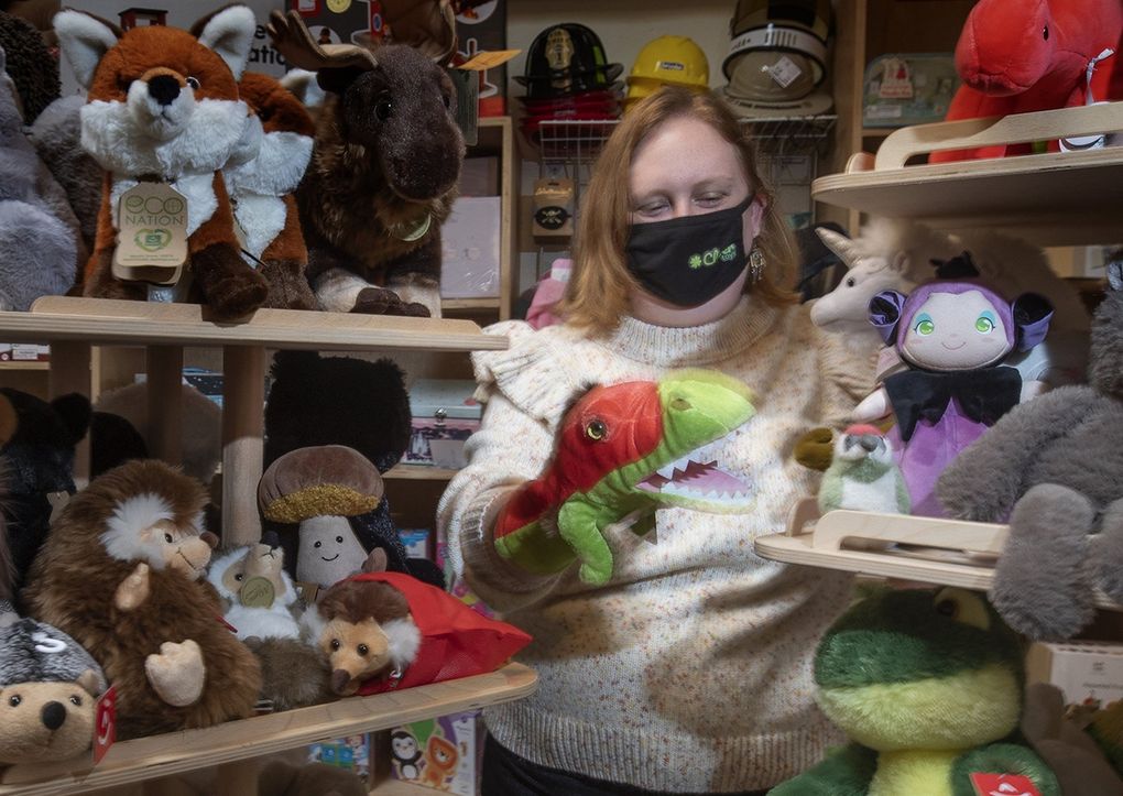 Brittney Geleynse, owner of Clover Toys in Ballard, holds up one of her popular hand puppets, a velociraptor. She has been unable to get some big-name toys, like Tonka, due to supply chain issues, but has found substitutes ahead of the Christmas shopping crunch. (Ellen M. Banner / The Seattle TImes)
