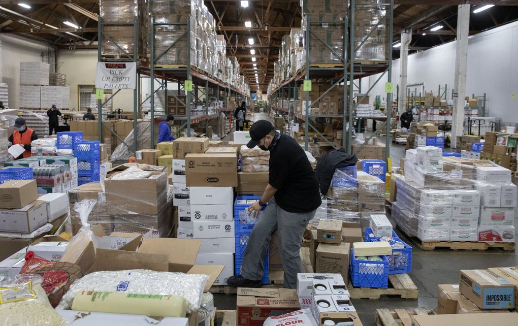 At Merlino Foods, a supplier to Western Washington restaurants, Charles Santa Cruz organizes pallets before loading his truck for delivery. Santa Cruz, a delivery driver at Merlino for more than four years, said part of his job lately is apologizing and explaining to customers about supply disruptions. (Ken Lambert / The Seattle Times)