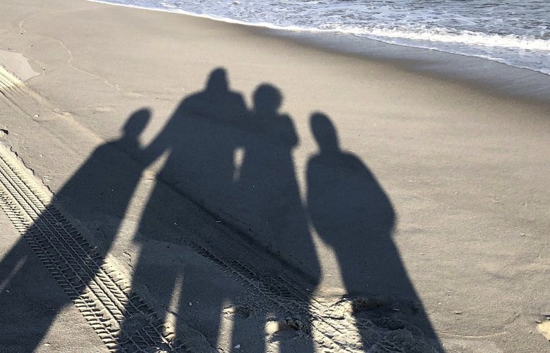 The shadows of Associated Press editor Pia Sarkar and her family are cast on the sand at Island Beach State Park in Berkeley Township, N.J., in November 2020. Since the start of the pandemic, Sarkar tried to play it safe, staying close to home, avoiding large gatherings, and limiting activities to the outdoors. Yet she and her kids still managed to get COVID. (AP Photo/Pia Sarkar) RPPS201 RPPS201