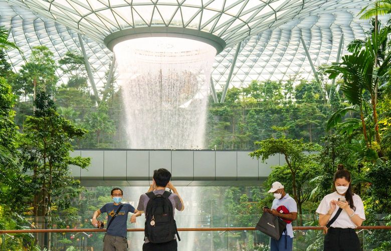 Visitors take photographs in front of the Rain Vortex indoor waterfall feature at the Jewel Changi Airport mall in Singapore, on Sunday, Oct. 3, 2021. Singapore Trade MinisterÂ Gan Kim Yong said the government is committed to reopening the country gradually after reimposing domestic curbs such as making work-from-home the default and cutting the number of diners to deal with a surge in cases. Photographer: Ore Huiying/Bloomberg 775719838