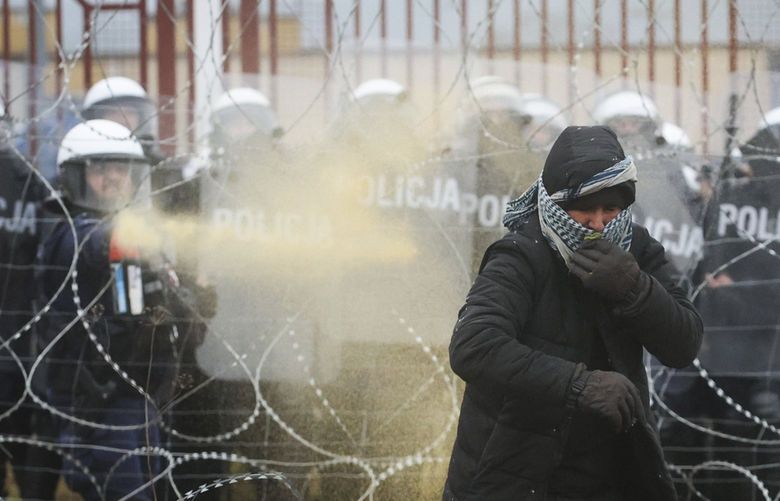 Polish serviceman sprays tear gas during clashes between migrants and Polish border guards at the Belarus-Poland border near Grodno, Belarus, on Tuesday, Nov. 16, 2021. Polish border forces say they were attacked with stones by migrants at the border with Belarus and responded with a water cannon. The Border Guard agency posted video on Twitter showing the water cannon being directed across the border at a group of migrants in a makeshift camp. (Leonid Shcheglov/BelTA via AP) XSG114 XSG114