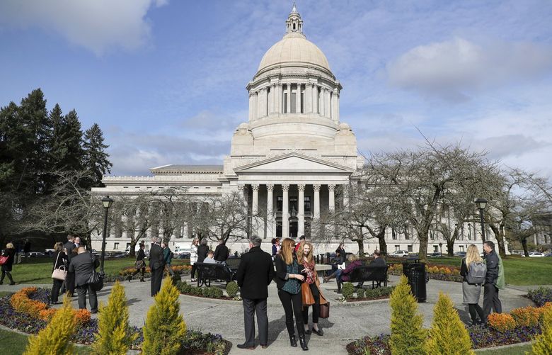 The Legislative Building stands out against a blue sky, Monday, Feb. 24, 2020, at the Capitol in Olympia, Wash. as pedestrians walk outside near the lunch hour. (AP Photo/Ted S. Warren) WATW103