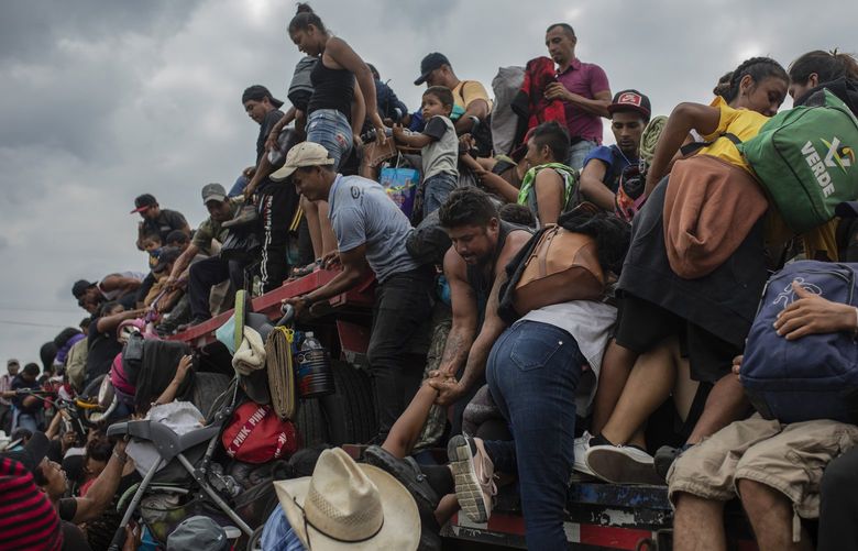 Migrants help fellow migrants onto the bed of a trailer in Jesus Carranza, in the Mexican state of Veracruz, Wednesday, Nov. 17, 2021.  A group of mainly Central American migrants are attempting to reach the U.S.-Mexico border. (AP Photo/Felix Marquez) XFM104 XFM104