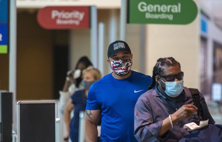 Masked passengers walk to the security checkpoint at Dallas Love Field airport in Dallas on July 26, 2020. A potential shortage of airport screeners triggered by a federal COVID-19 vaccine mandate could mean extra-long queues during the upcoming Thanksgiving holiday travel week. (Lynda M. Gonzalez/Dallas Morning News/TNS) 32503104W 32503104W