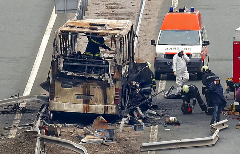 Firefighters and forensic workers inspect the scene of a bus crash on a highway near the village of Bosnek, western Bulgaria, Tuesday, Nov. 23, 2021. A bus carrying tourists back to North Macedonia crashed and caught fire in western Bulgaria early Tuesday, killing at least 45 people, including a dozen children, authorities said. (Minko Chernev/BTA Agency Bulgaria via AP) XAA208 XAA208