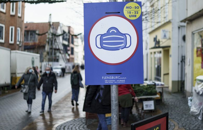 A sign indicating COVID-19 restrictions of mandatory masks hangs on a post along a pedestrian street in Flensburg, Germany, Wednesday, Nov. 24, 2021.(Roland Weihrauch/dpa via AP) BBL819 BBL819