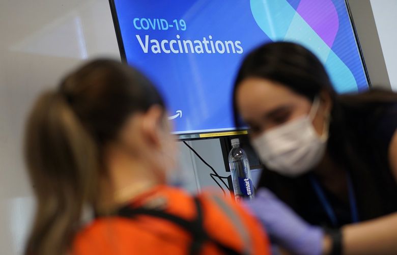 FILE – Registered nurse Sofia Mercado, right, administers a COVID-19 vaccine at a vaccination event for workers at an Amazon Fulfillment Center in North Las Vegas, Nev., on March 31, 2021. State health officials said Friday, Nov. 19, 2021, that COVID-19 vaccine booster shots are now available for all Nevada adults. (AP Photo/John Locher, File) FX503 FX503