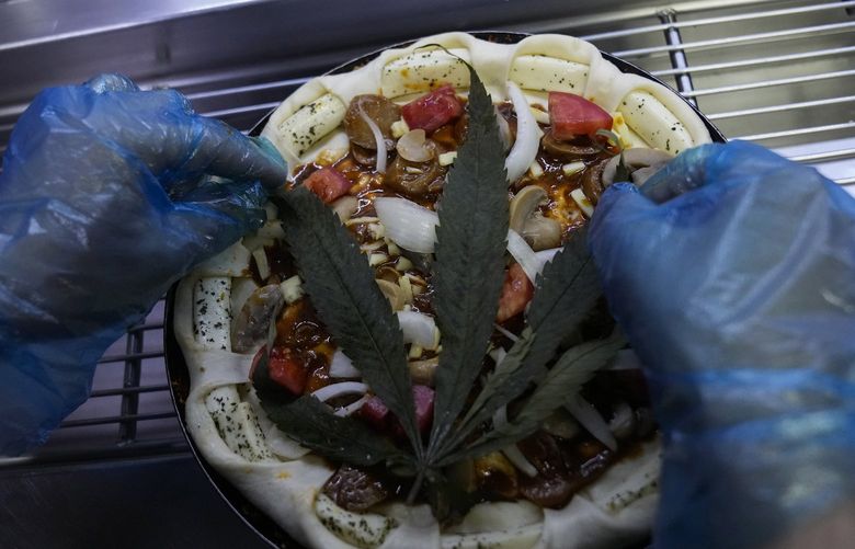 A cannabis leaf is put on a pizza at a restaurant in Bangkok, Thailand on Nov. 24, 2021. The Pizza Company, a Thai major fast food chain, has been promoting its “Crazy Happy Pizza” this month, an under-the-radar product topped with a cannabis leaf. It’s legal but won’t get you high. (AP Photo/Sakchai Lalit) XSL101 XSL101