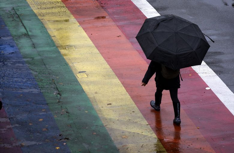 A pedestrian crosses the street at the intersection of East Pike Street and Broadway Thursday, Oct. 28, 2021.  Rain is expected over the weekend in Seattle. (Ellen M. Banner / The Seattle TImes)