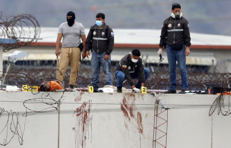 EDS NOTE: GRAPHIC CONTENT – The body of a prisoner lies next to police on the roof of the Litoral penitentiary the morning after riots broke out inside the jail in Guayaquil, Ecuador, Saturday, Nov. 13, 2021. (AP Photo/Jose Sanchez) DOR103 DOR103