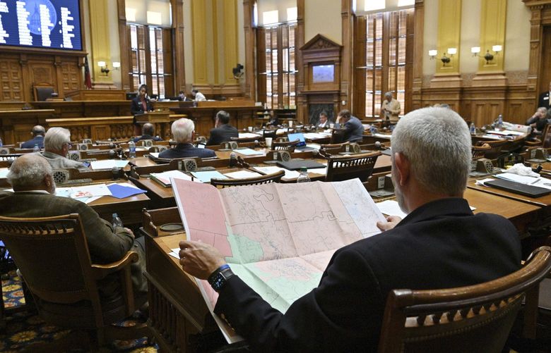 Chuck Payne, R-Dalton, foreground, looks at a map as Nikki Merritt, D-Grayson, background, speaks in opposition of Senate Bill 2EX, newly-drawn congressional maps, in the Senate Chambers during a special session at the Georgia State Capitol in Atlanta, Friday, Nov. 19, 2021. (Hyosub Shin/Atlanta Journal-Constitution via AP) GAATJ400 GAATJ400