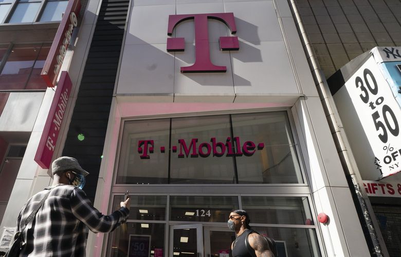 A man uses a mobile phone outside a T-Mobile store, Monday, April 19, 2021,  in New York. The wireless carrier agreed to pay $19.5 million in a settlement with the Federal Communications Commission over a 12-hour nationwide outage in June 2020 that resulted in thousands of failed 911 calls. The FCC said Tuesday, Nov. 23 that as part of the settlement, T-Mobile will also commit to improving communications of outages to emergency call centers, among other measures. (AP Photo/Mark Lennihan) NYBZ900 NYBZ900