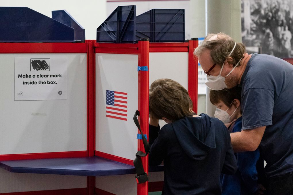 Sean Luke, right, and his sons Giacomo Luke, left, and Matteo Luke, casts his ballot on Election Day at City Hall, Tuesday, Nov. 2, 2021 in Alexandria, Va. Voters are deciding between Democrat Terry McAuliffe and Republican Glenn Youngkin for Governor. (AP Photo/Alex Brandon)