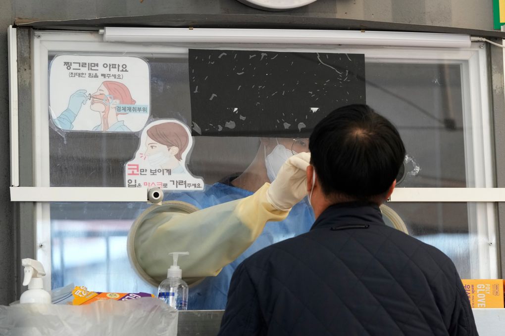 A medical worker in a booth takes a nasal sample from a man at a makeshift testing site in Seoul, South Korea, Wednesday, Nov. 24, 2021. New coronavirus infections in South Korea exceeded 4,000 in a day for the first time since the start of the pandemic as a delta-driven spread continues to rattle the country after it eased social distancing in recent weeks to improve its economy. (AP Photo/Ahn Young-joon).