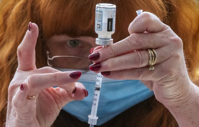 Barbara Hoffman, a community health program manager and R. N., taps bubbles out of a syringe filled with the COVID-19 vaccine as people line up in their cars in the parking garage at the Suquamish Clearwater Casino Resort in Suquamish Wednesday, March 17, 2021, waiting to be vaccinated. A vaccine clinic run by the Suquamish Tribe has been set up for teachers and others from the North Kitsap School District and approximately 220 people are being vaccinated Wednesday. Ten to twelve people are vaccinated every 20 minutes during three morning and three afternoon hours. Native communities are helping speed the teacher vaccination efforts with COVID-19 vaccines.