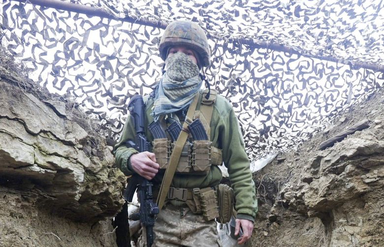 Ukrainian soldiers walks under a camouflage net in a trench on the line of separation from pro-Russian rebels near Debaltsevo, Donetsk region, Ukraine, Ukraine Friday, Dec 3, 2021. In this Friday, the Ukrainian defense minister warned that Russia could invade his country next month. Russia-West tensions escalated recently with Ukraine and its Western backers becoming increasingly concerned that a Russian troop buildup near the Ukrainian border could signal Moscow’s intention to invade. XEL103