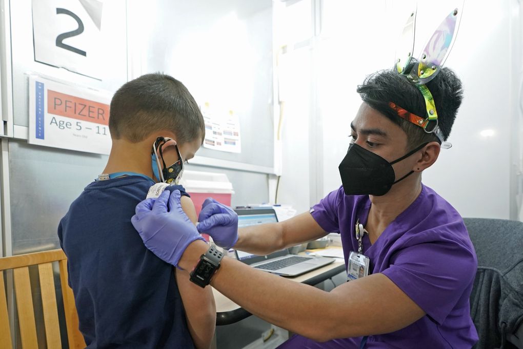 Andre Mattus, a nurse at the University of Washington Medical Center, gives the first shot of the Pfizer COVID-19 vaccine to Amar Gunderson, 6 1/2, last month, in Seattle. (Ted S. Warren / AP)