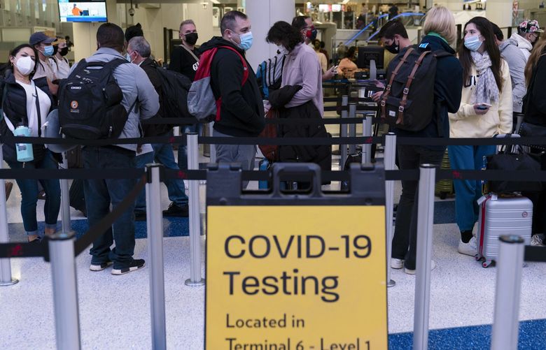 FILE – Travelers wait in line for screening near a sign for a COVID-19 testing site at the Los Angeles International Airport in Los Angeles on Nov. 24, 2021. Beginning next week, travelers heading to the U.S. will be required to show evidence of a negative test for the virus within one day of boarding their flight. The previous period was three days. (AP Photo/Jae C. Hong, File) NYDD201 NYDD201